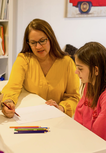 Sim working one-on-one with a young student on writing